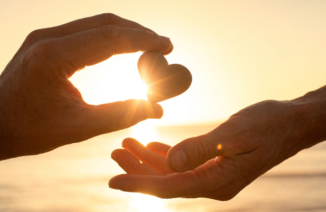 Hands holding a heart in sunlight